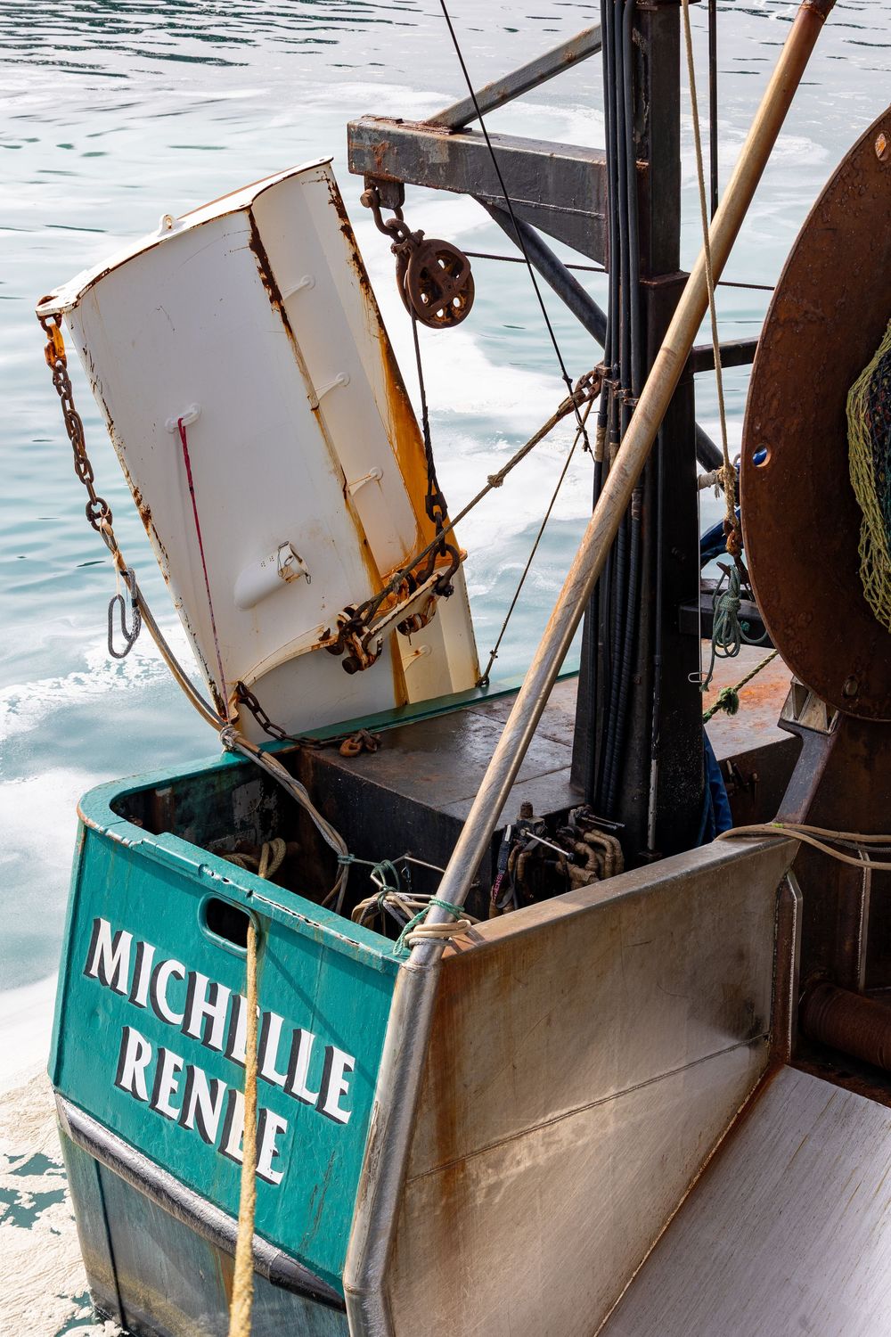 Detail of a fishing boat named Michelle Renee showing equipment and rigging against rippling water.