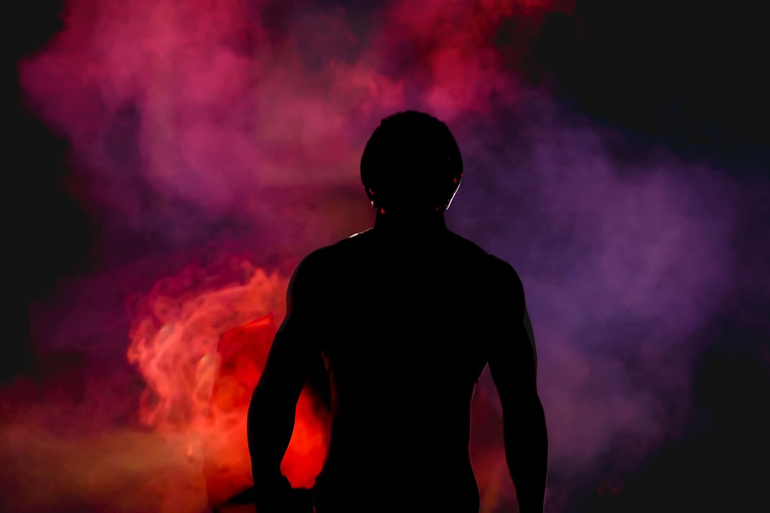 A boxer wearing a black sports bra stands in the ring with dramatic backlighting during a match.