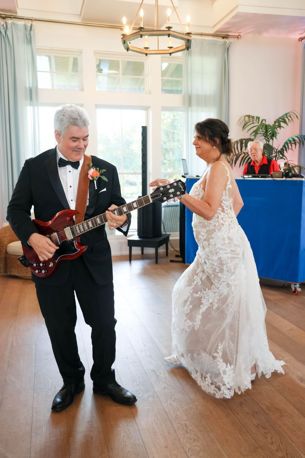 A dance moment captured during a wedding reception with a guitar performance on a wooden floor.