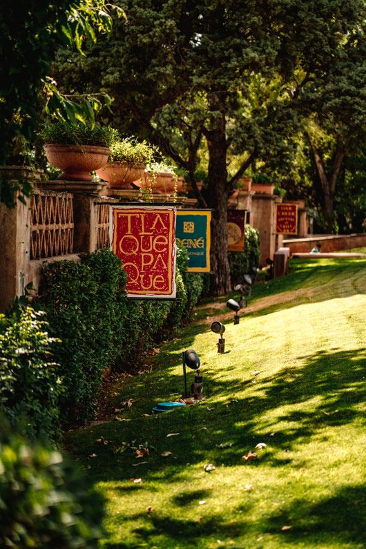 Sedona garden pathway with red sign and potted plants along a green lawn in afternoon light.