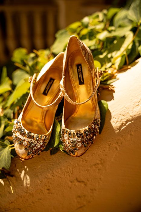 Ornate bridal shoes with crystal embellishments on a textured surface.