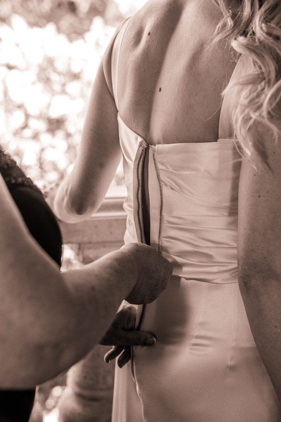 Sepia-toned image of a wedding dress being laced up.