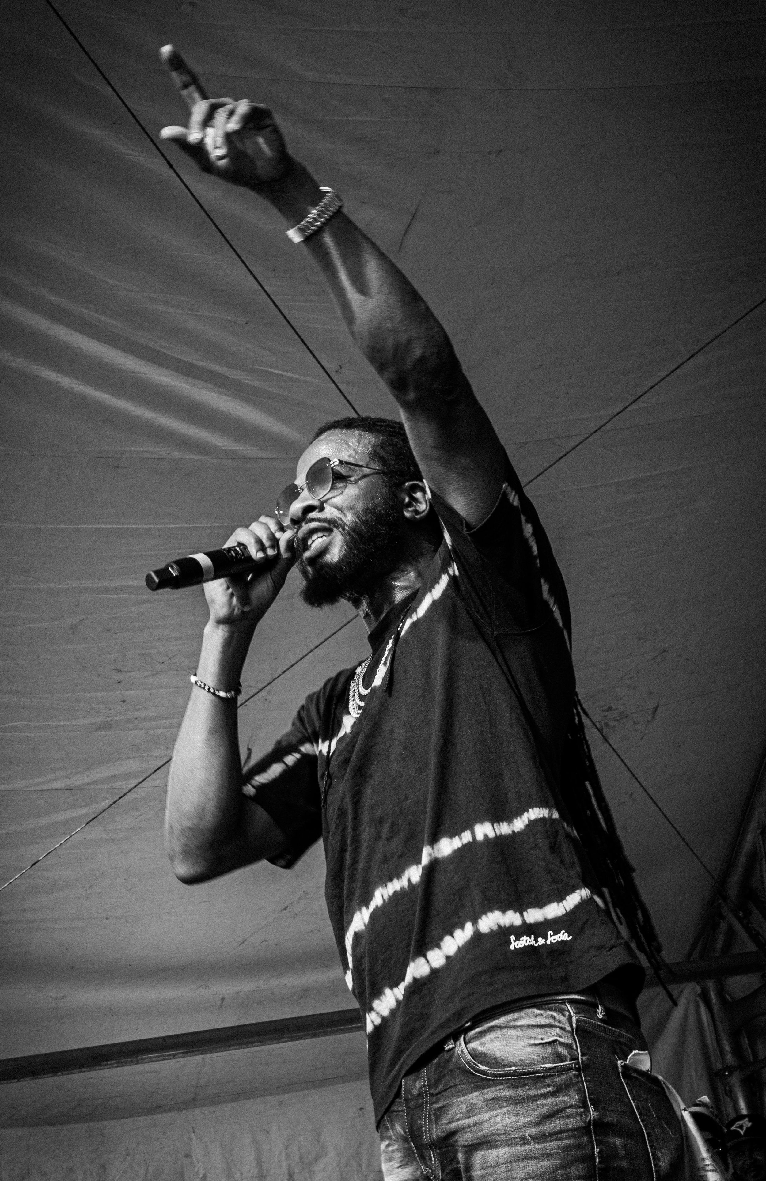 Gyptian Concert Calgary. A black and white photo of Gyptian as he sings into the mic in his right hand and points to the sky with his left.