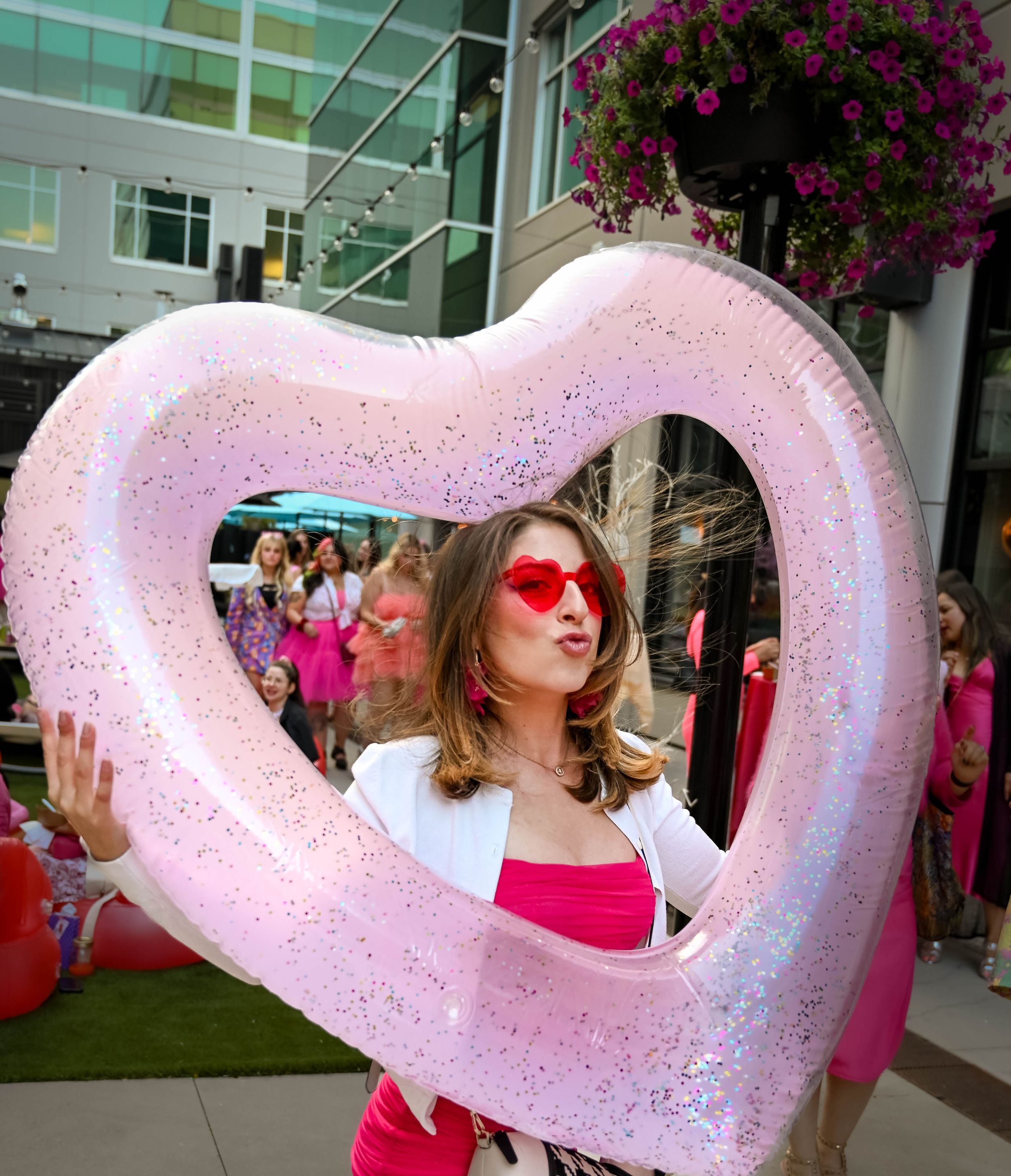Barbie Block Party. A woman wearing pink heart glasses peeps through a heartshaped balloon.