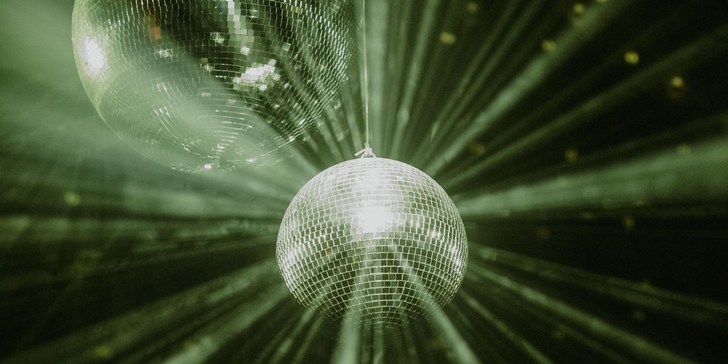 Close-up of green disco balls with dramatic light beams during a luxury wedding party in Tulum.