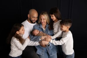 Family wearing white shirts and denim gather closely together. NJ newborn photographer in Sussex County NJ