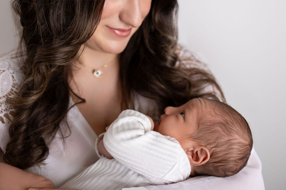 A series of intimate black and white photos showing a parent holding and bonding with their newborn baby.