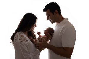 Silhouetted family portraits showing intimate moments between parents and baby against white backdrop.