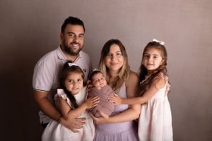 Family of 5 poses together against a neutral background in coordinated pink and white outfits. NJ newborn photographer in Sussex County NJ