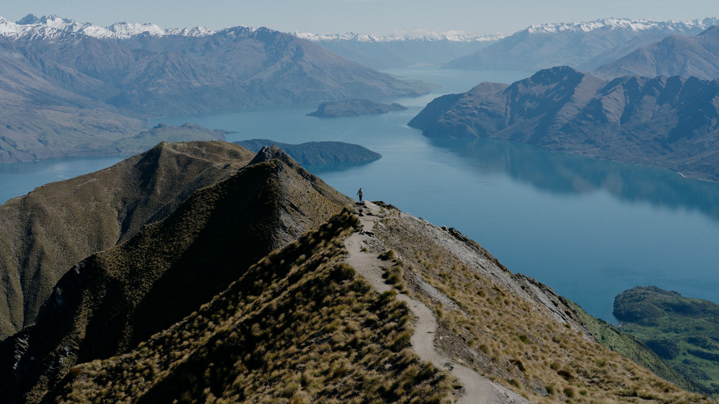 Dramatic mountain ridge overlooking a blue alpine lake surrounded by rugged peaks.