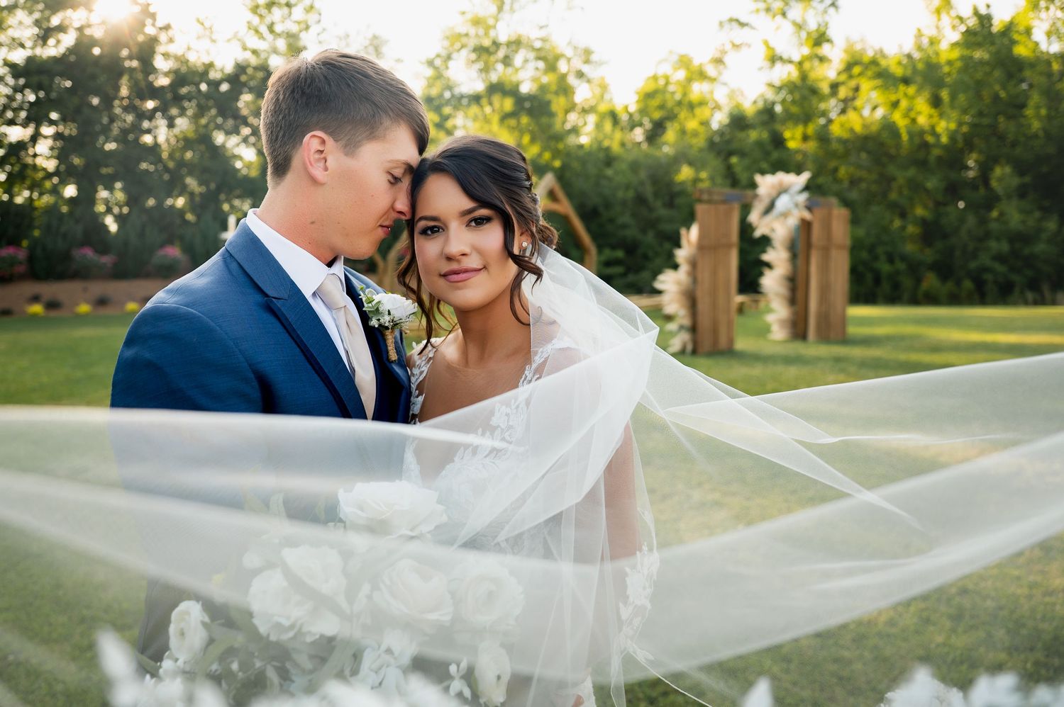 Romantic sunset wedding portrait with flowing veil in golden light.