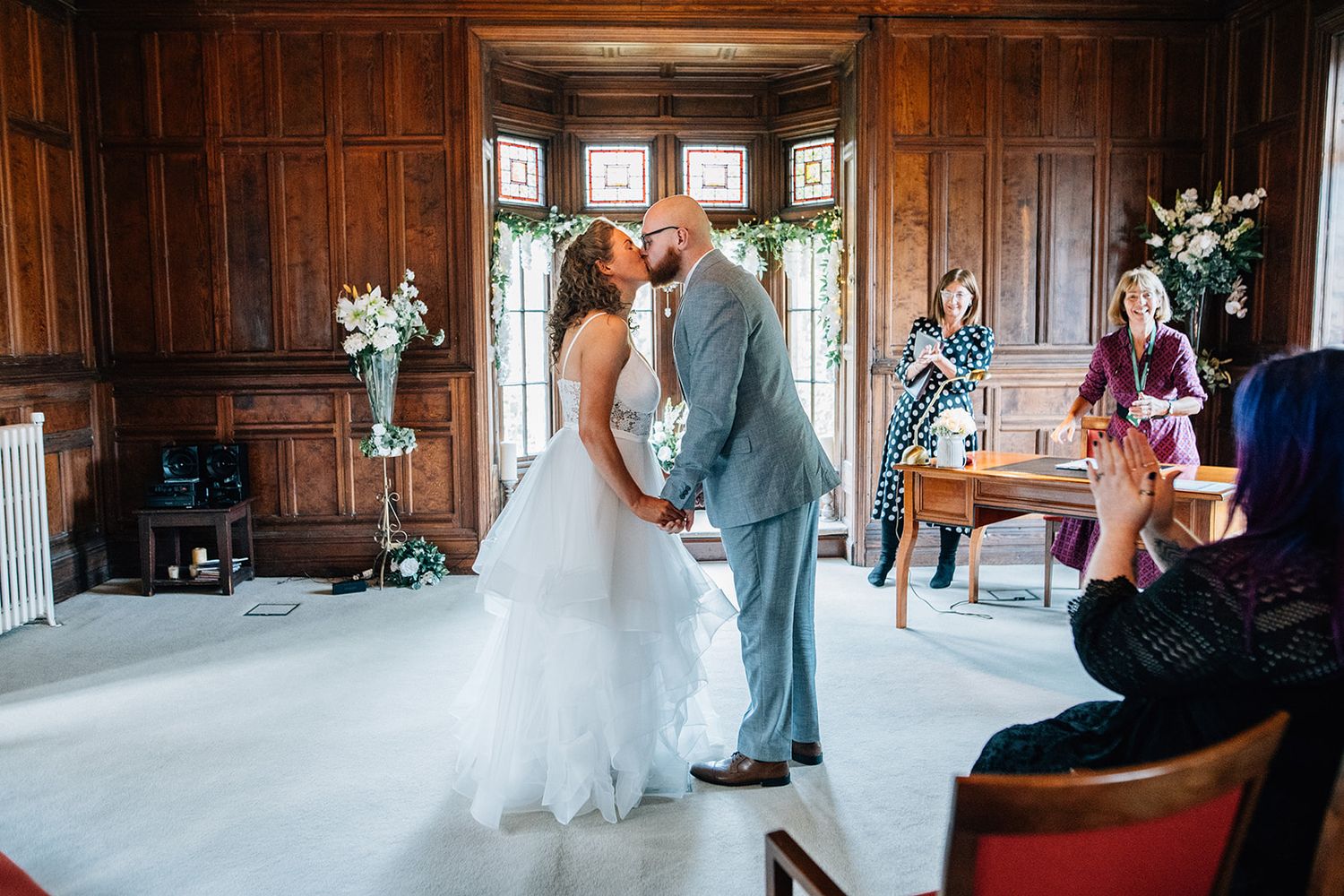 A series of wedding photos showing a couple and guests in an elegant wood-paneled venue with ornate architectural details.