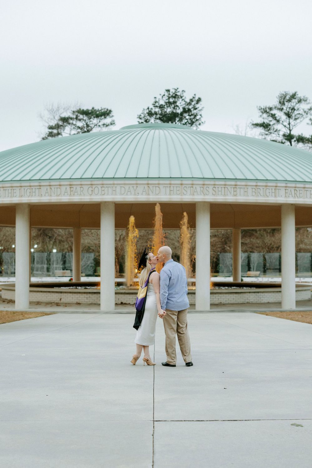 Modern covered pavilion with mint green roof and white columns in a park setting.