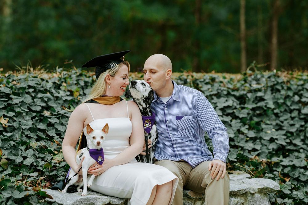 A couple sits together on a wooden bench in a lush garden setting during a romantic outdoor photo session.