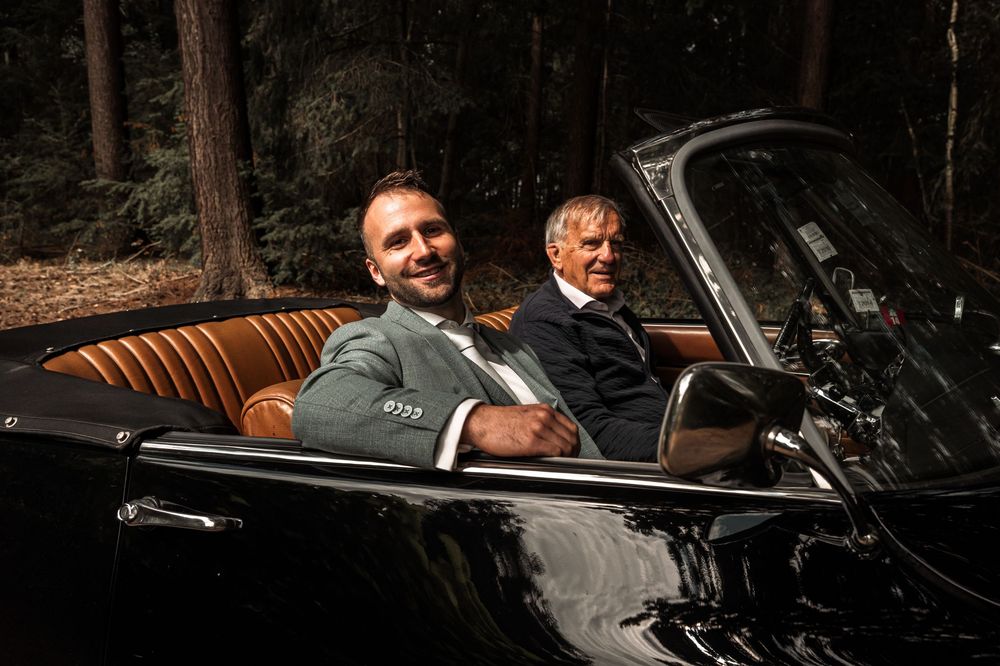 A classic car ride with passengers enjoying a sunny day.
