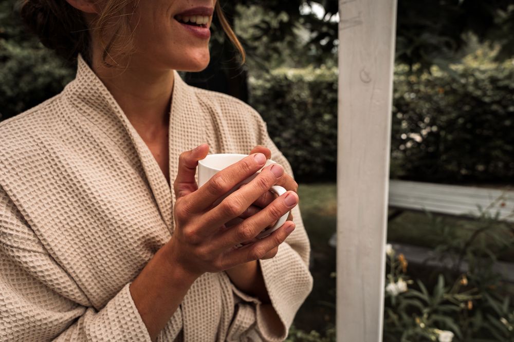 Close-up shots of someone holding a coffee cup while wearing a beige cardigan.