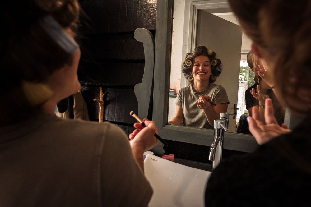 Wedding preparations showing makeup application in a softly lit room.