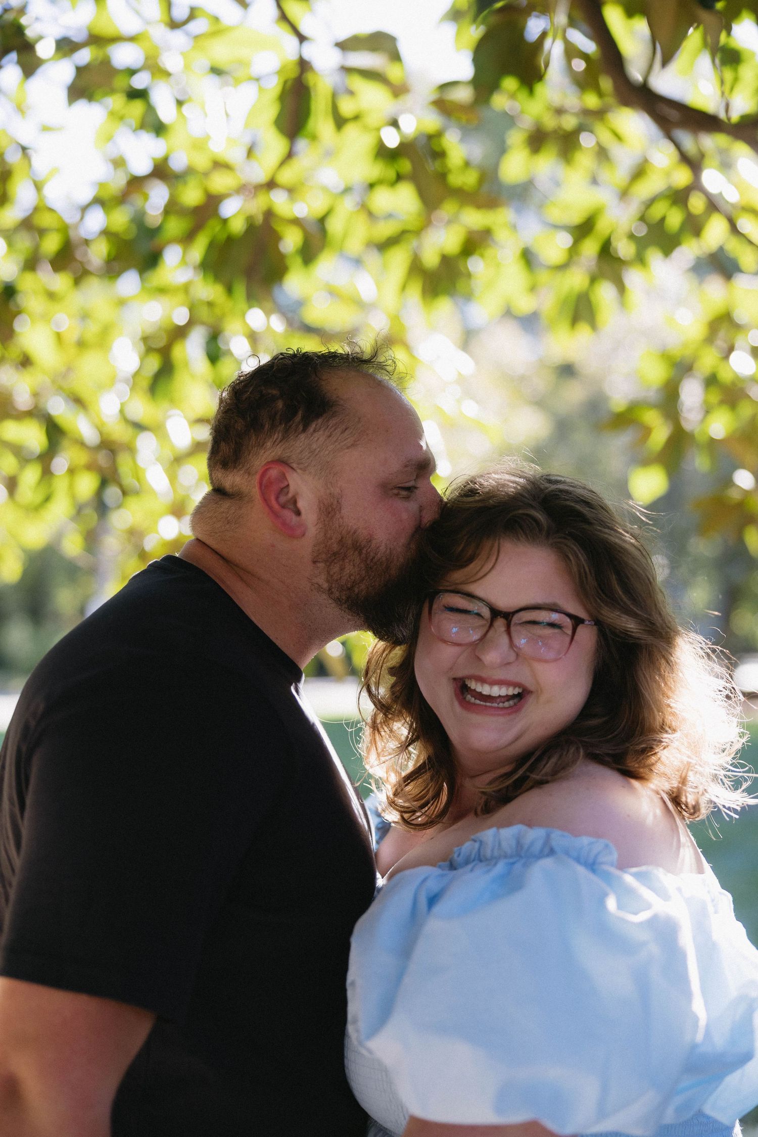 A couple shares tender moments in a series of romantic outdoor photos with sunlit trees in the background.