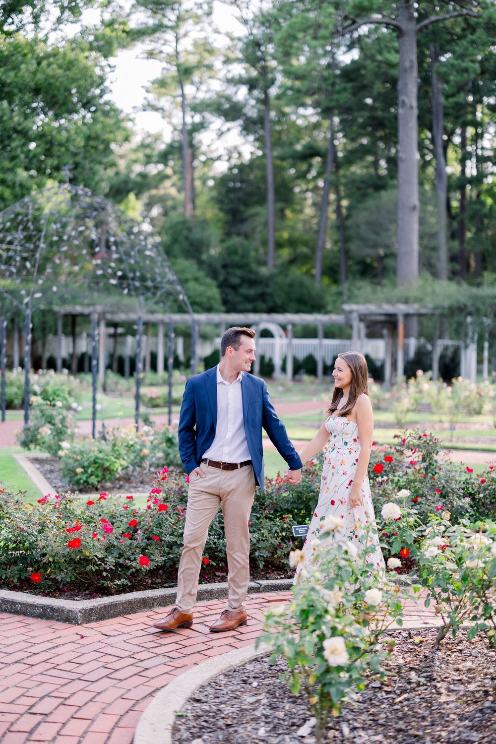 Romantic garden photoshoot among blooming roses and brick pathways.