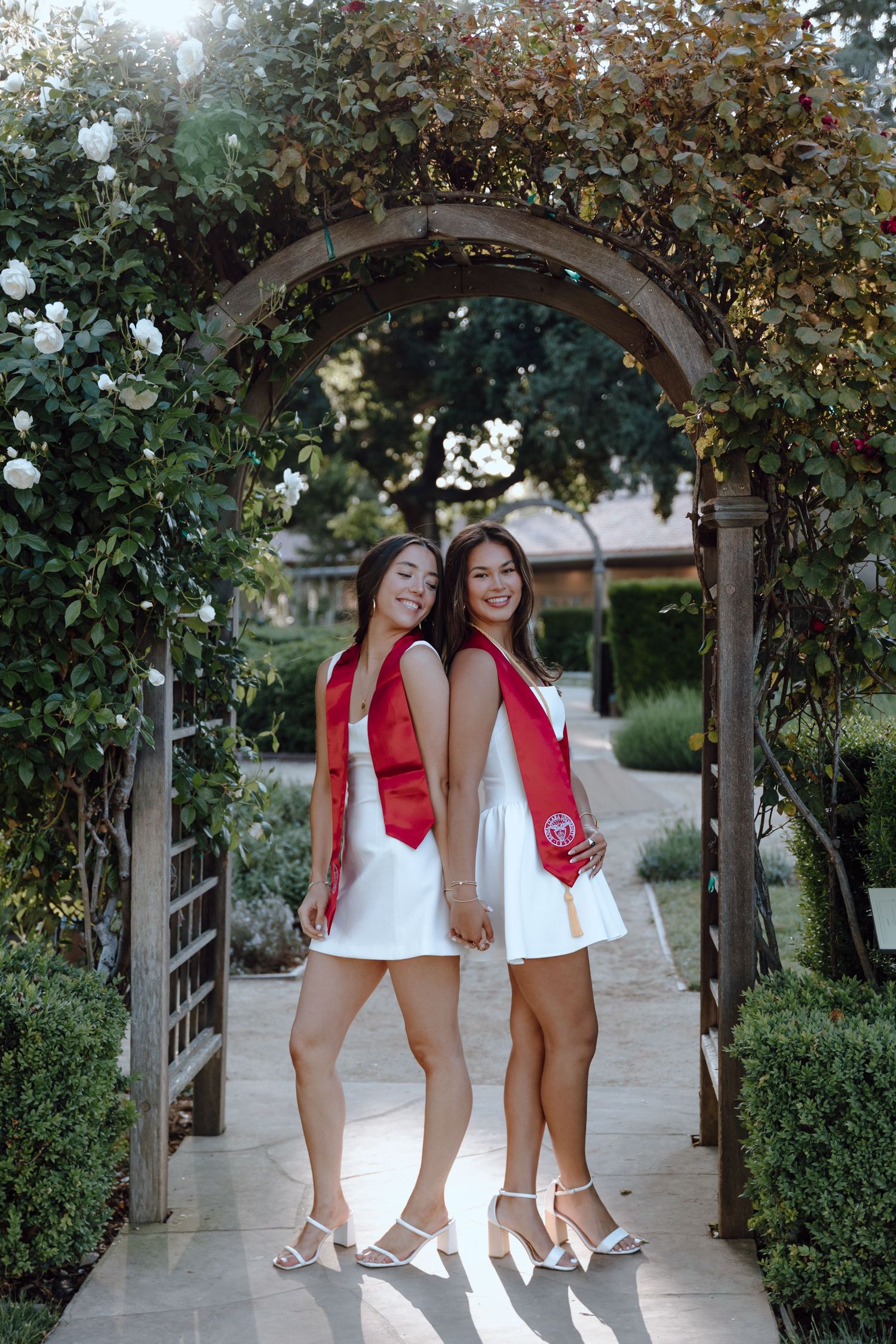 Two Santa Clara University graduates pose for bestiegrad photoshoot by standing under an archway. Taken by Bay Area Graduation Photographer.