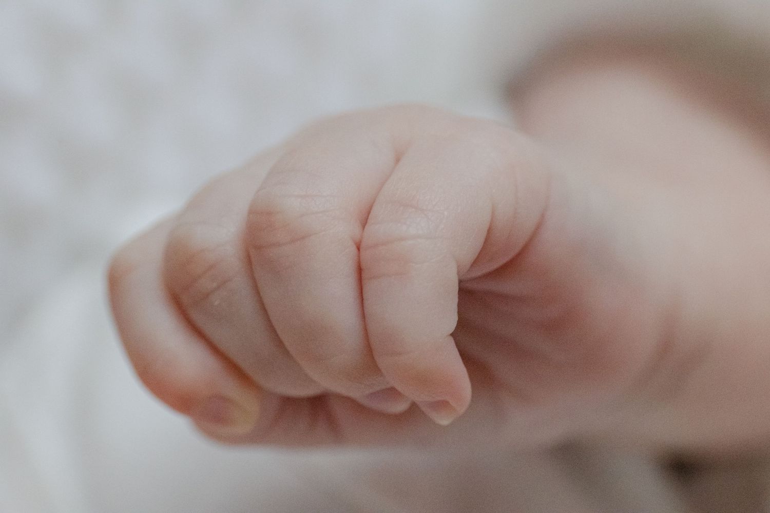 Close-up photo of tiny newborn baby toes and feet against a soft white background. CT Photographer