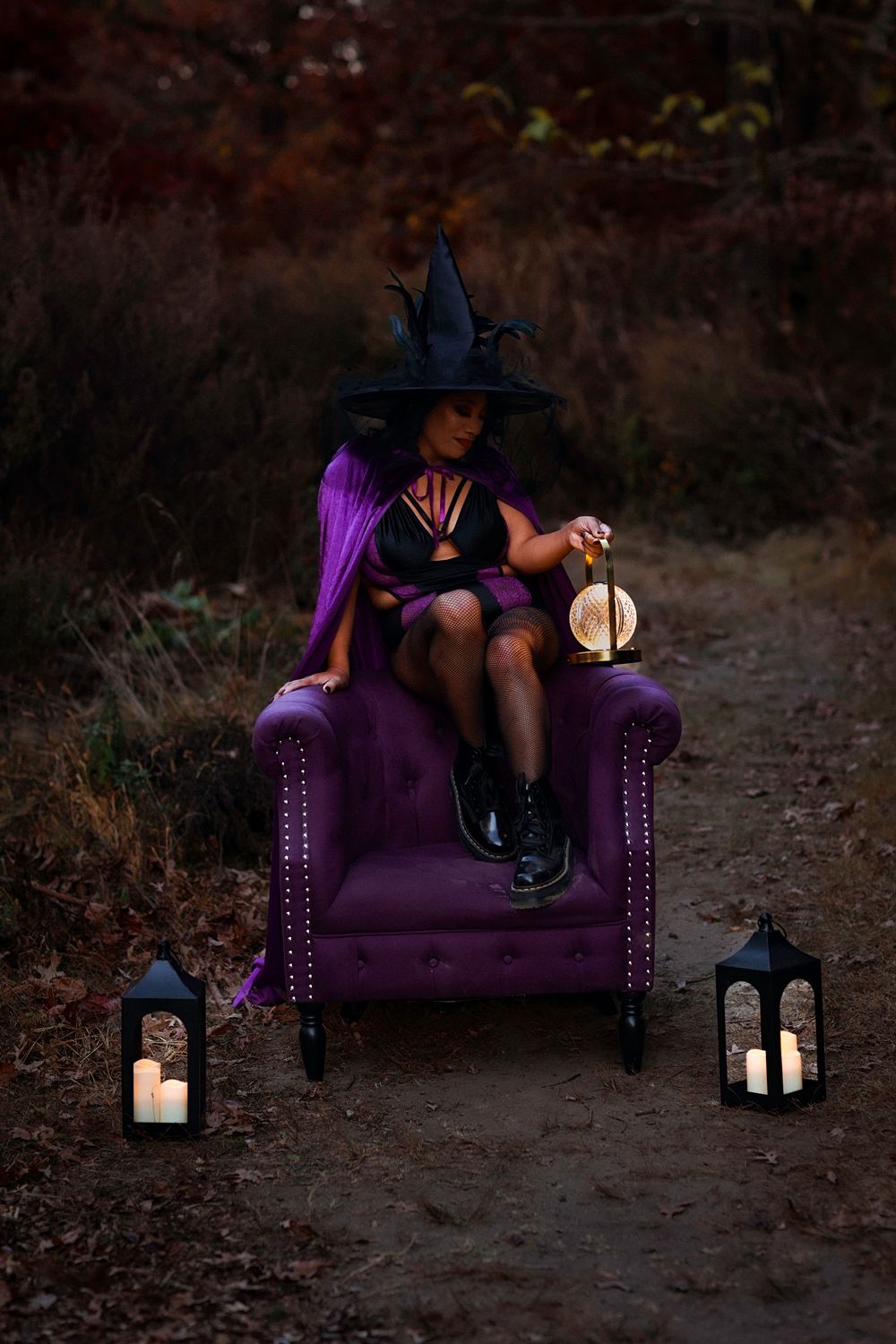 A purple velvet armchair sits outdoors at dusk with lanterns glowing atmospherically in a witchy Halloween setting.