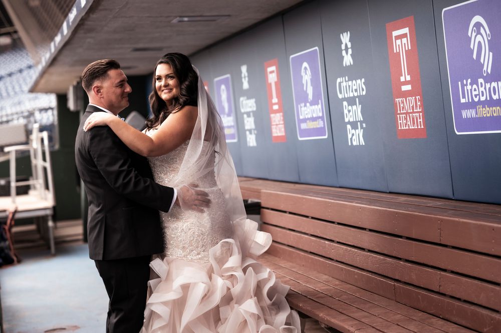 A couple in formal attire shares a romantic moment together on a wooden bench at an event venue.