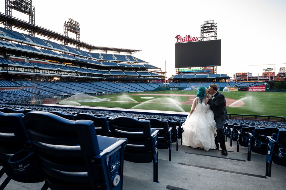 Wedding couple standing in empty stadium seats at Citizens Bank Park baseball stadium in Philadelphia.