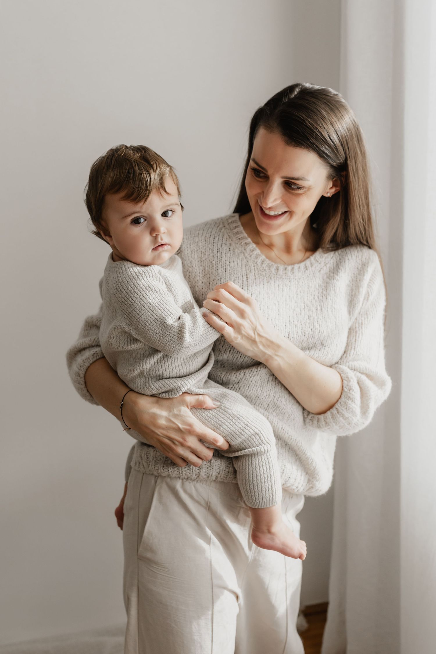 Mama mit Kleinkind auf dem Arm bei einem Mama & Me Fotoshooting im Fotostudio Stockerau für natürliche Kinderfotos