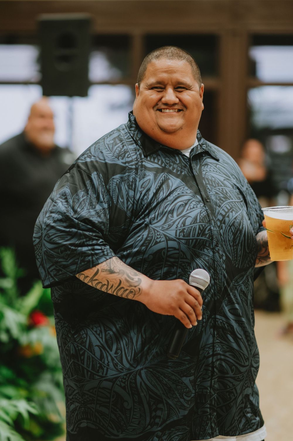 Person in dark patterned outfit smiling and enjoying festivities at an indoor event.
