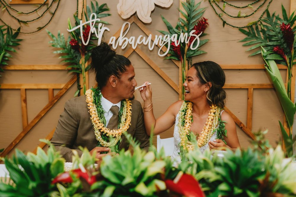 Wedding reception space decorated with tropical greenery and white floral accents.
