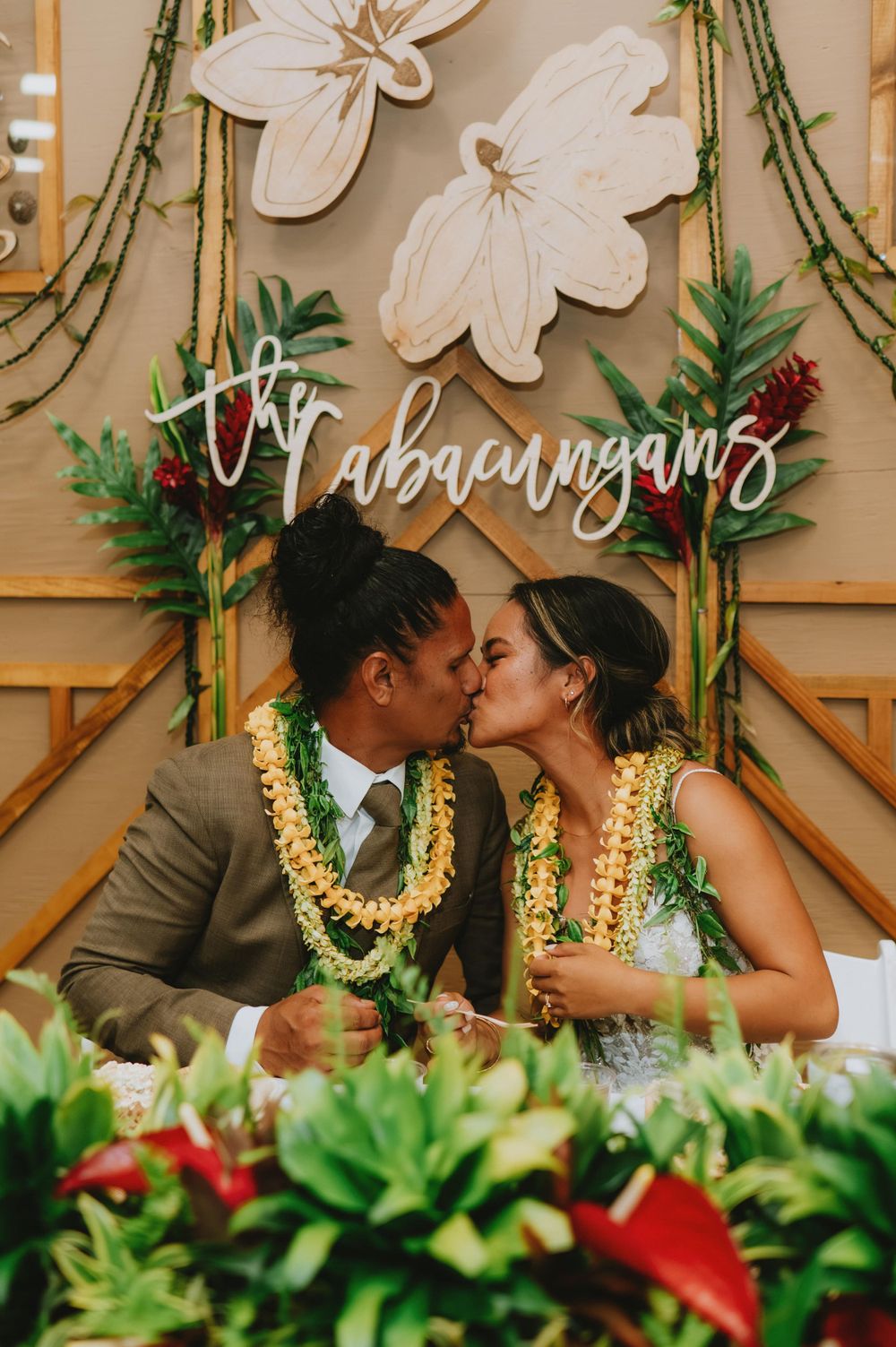 Wedding backdrop decorated with white flowers and tropical greenery.