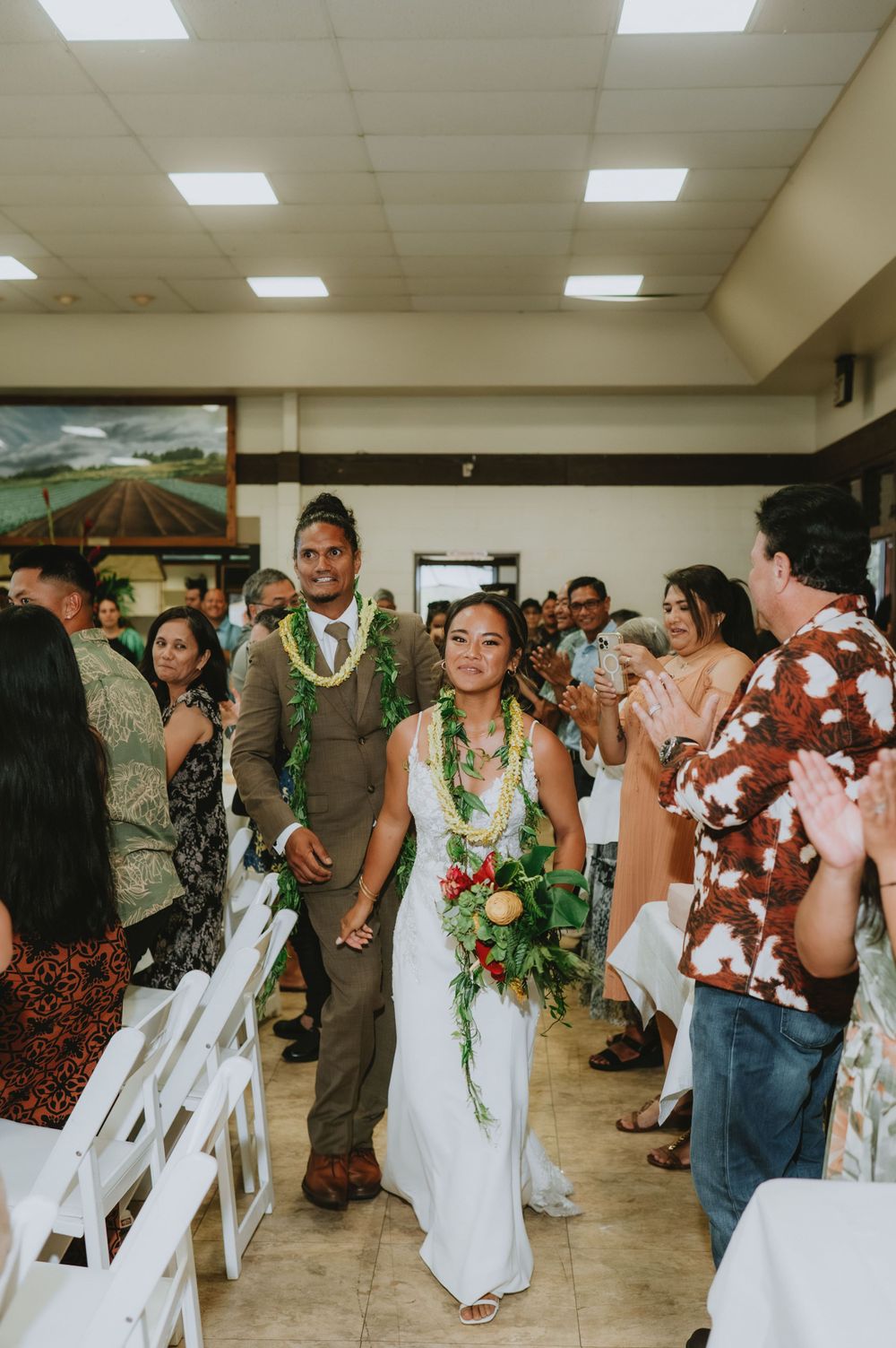 Wedding celebration in an indoor venue with tropical decorations.