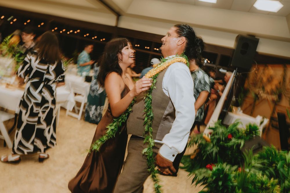 Guests mingling at an indoor wedding reception with tropical decor.
