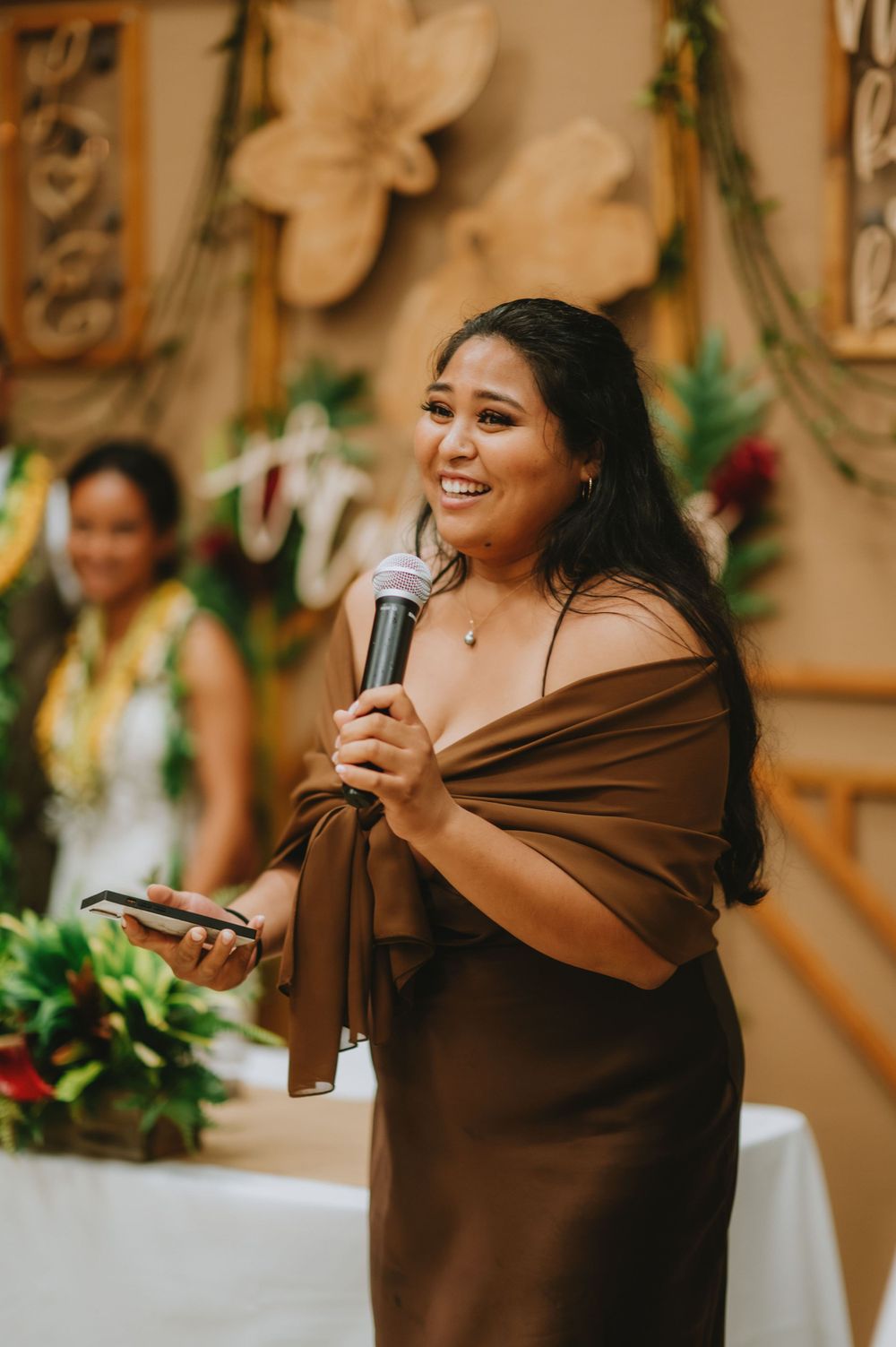Woman in brown dress giving an emotional speech at a wedding reception.
