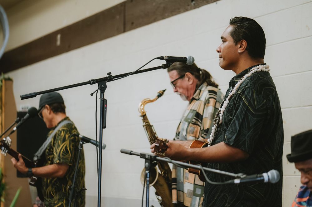 Musicians performing with instruments and microphones at an indoor event.