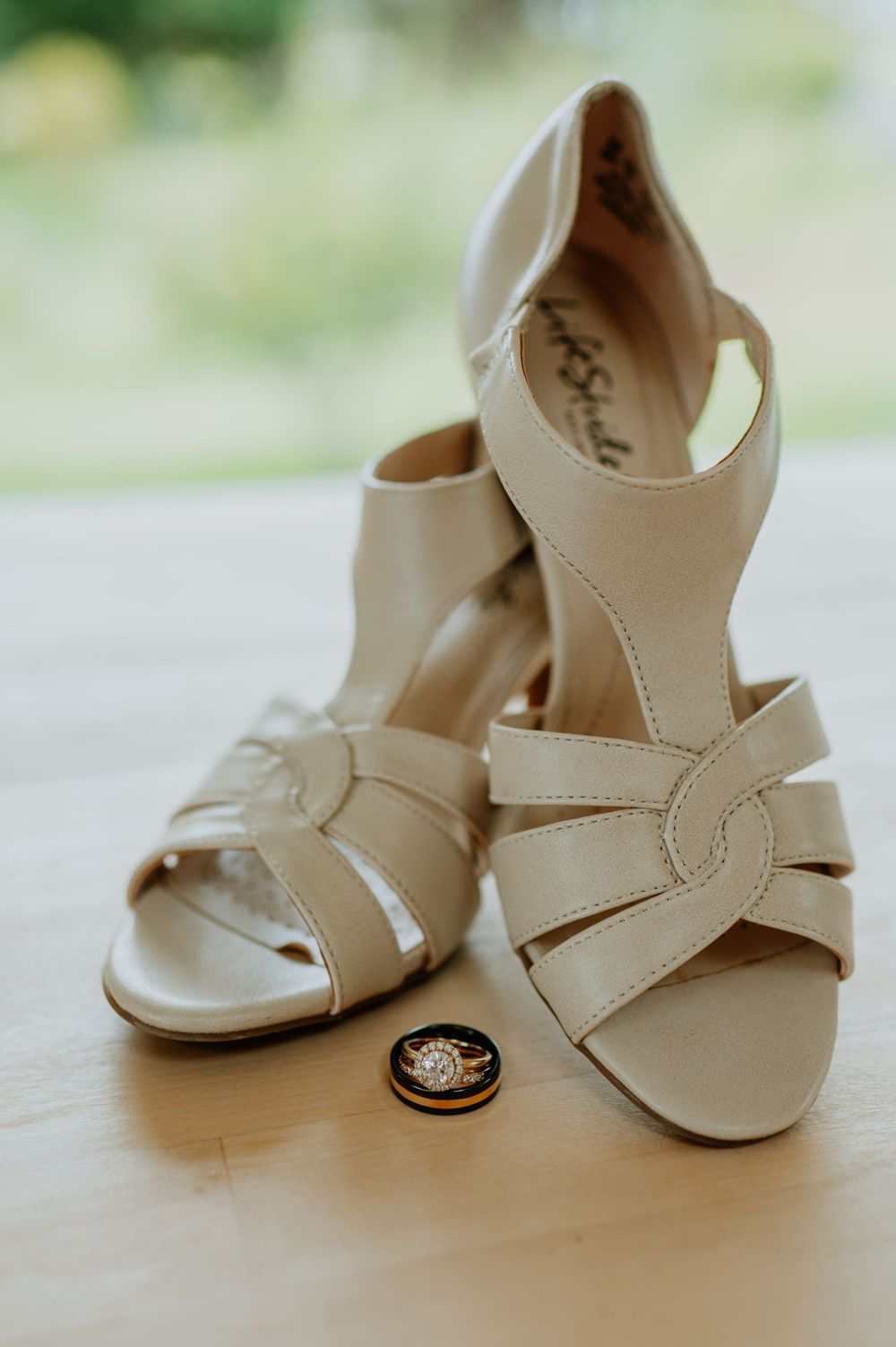 Elegant cream colored bridal sandals with wedding ring detail on light surface.