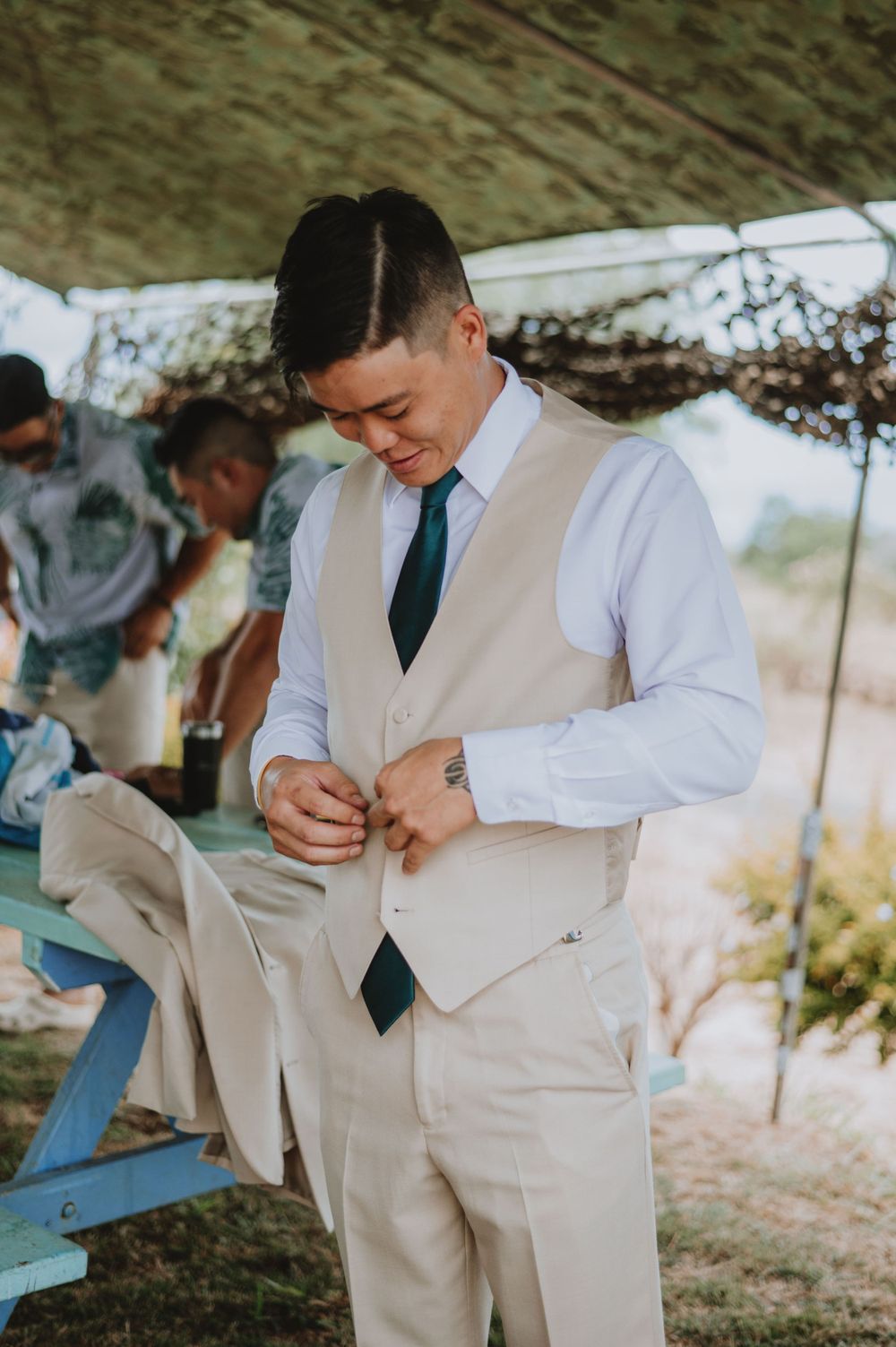 Groom in cream colored suit makes final adjustments before the ceremony.