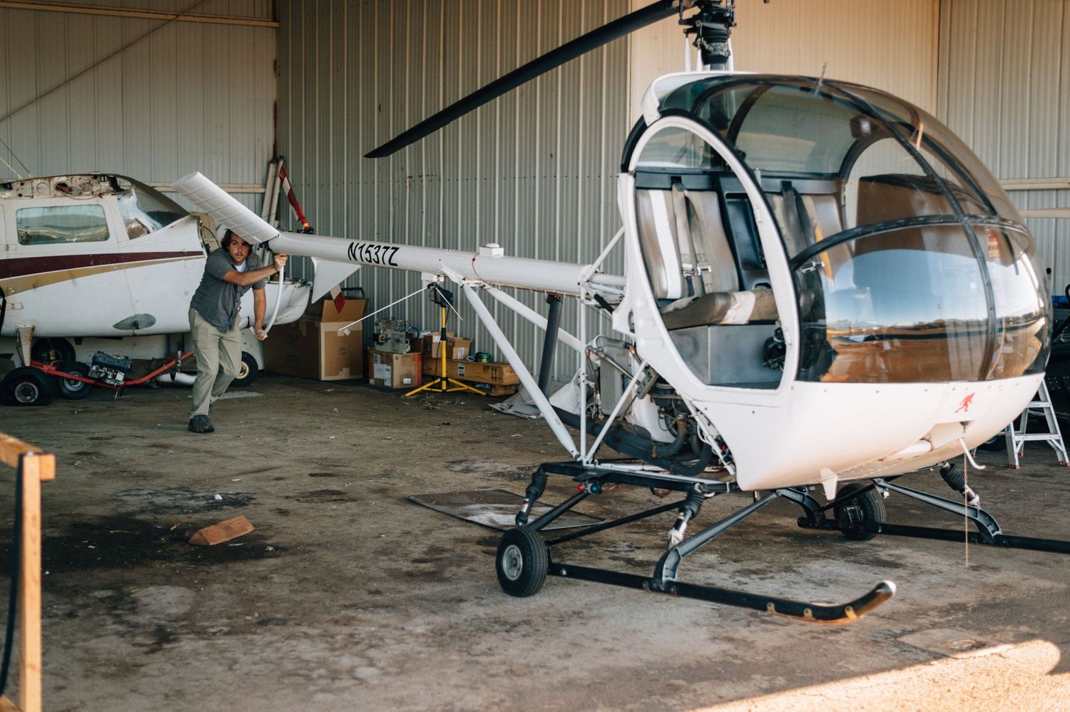 Multiple small aircraft parked inside an aviation hangar with wooden beams.