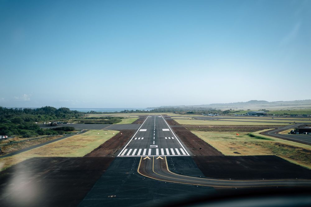 Aerial view of airport runway with clear markings against blue sky.