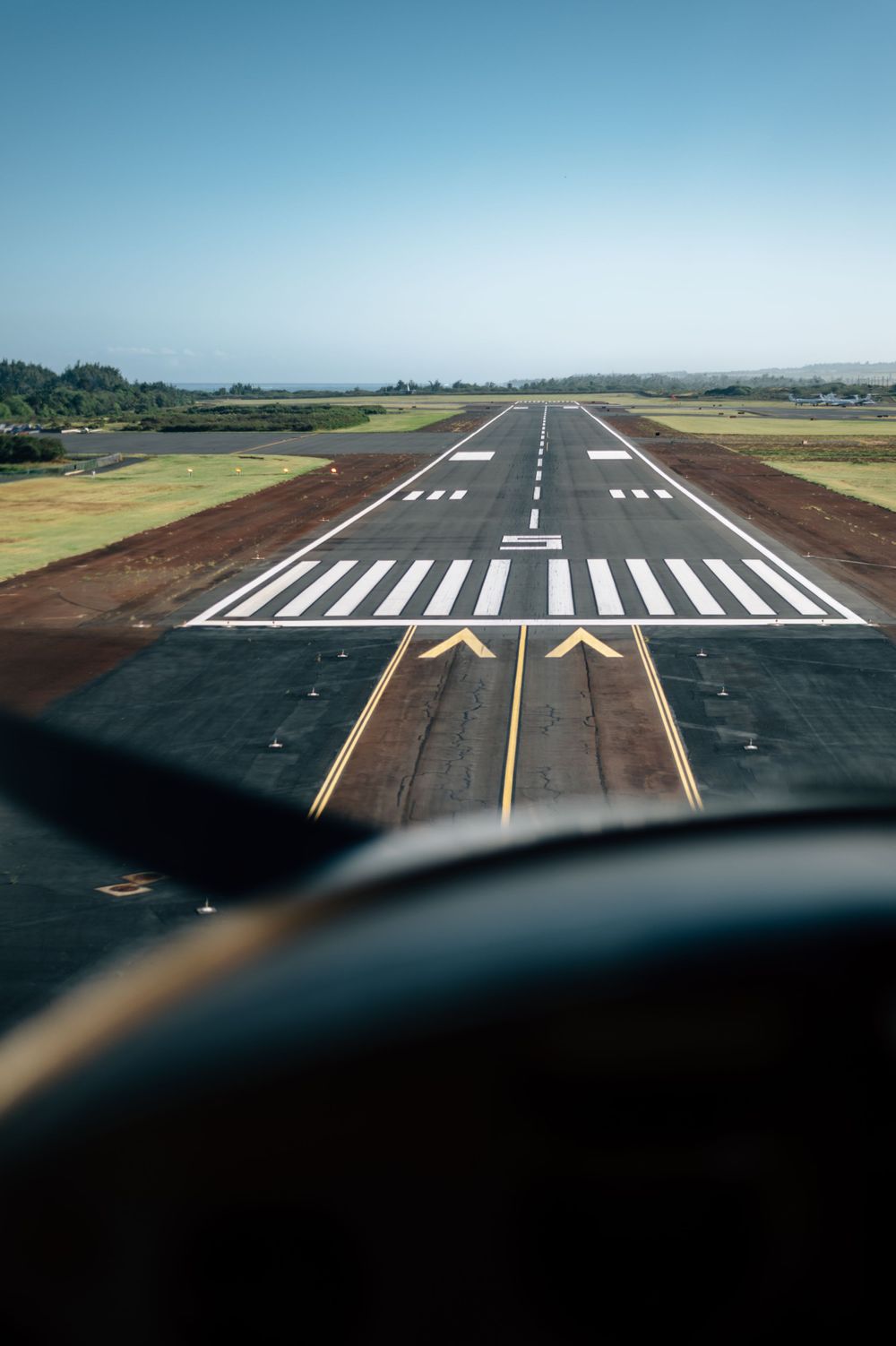 Aircraft approaching runway threshold markings during landing.