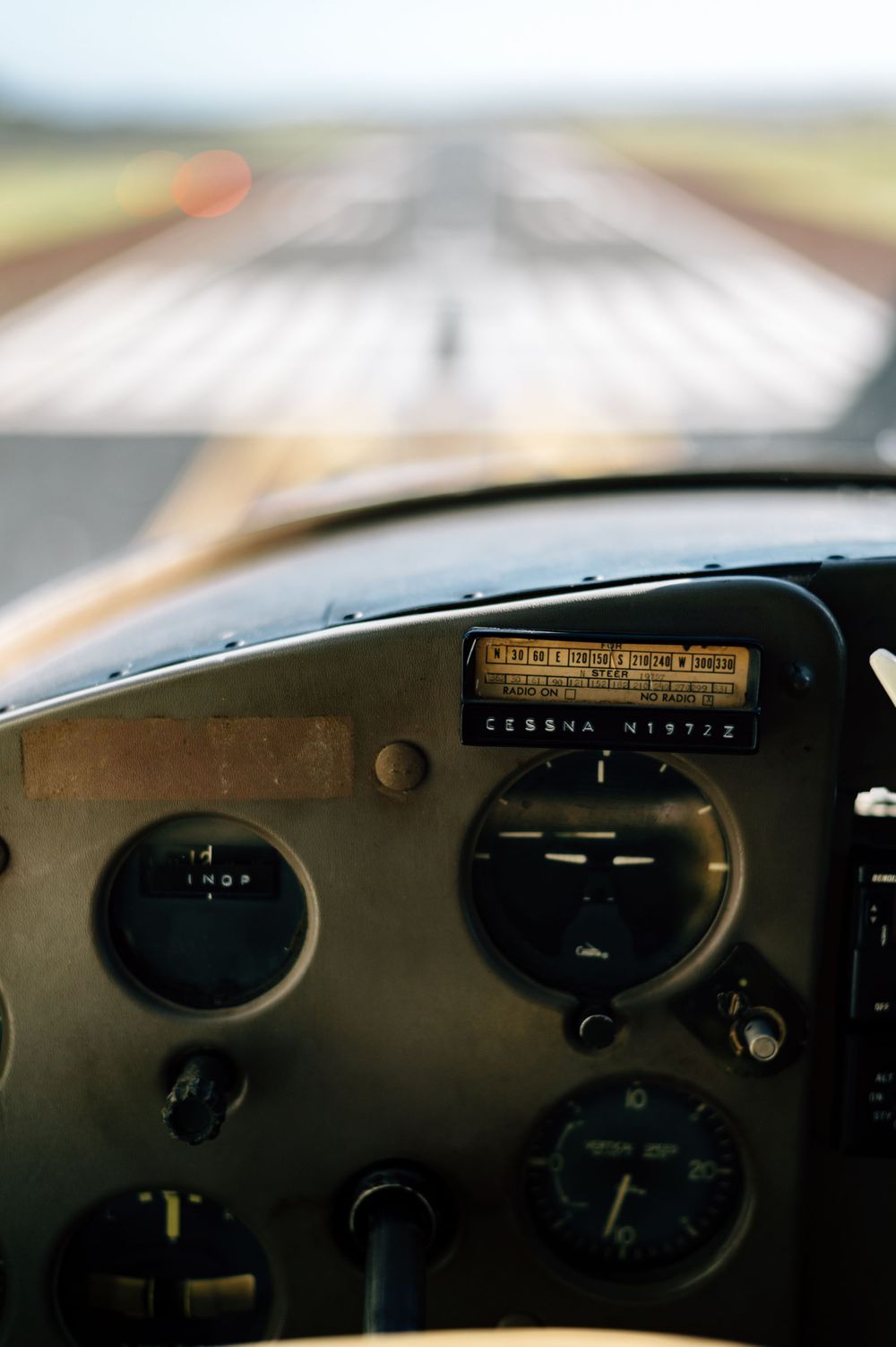 View through aircraft windshield showing flight instruments and runway ahead.