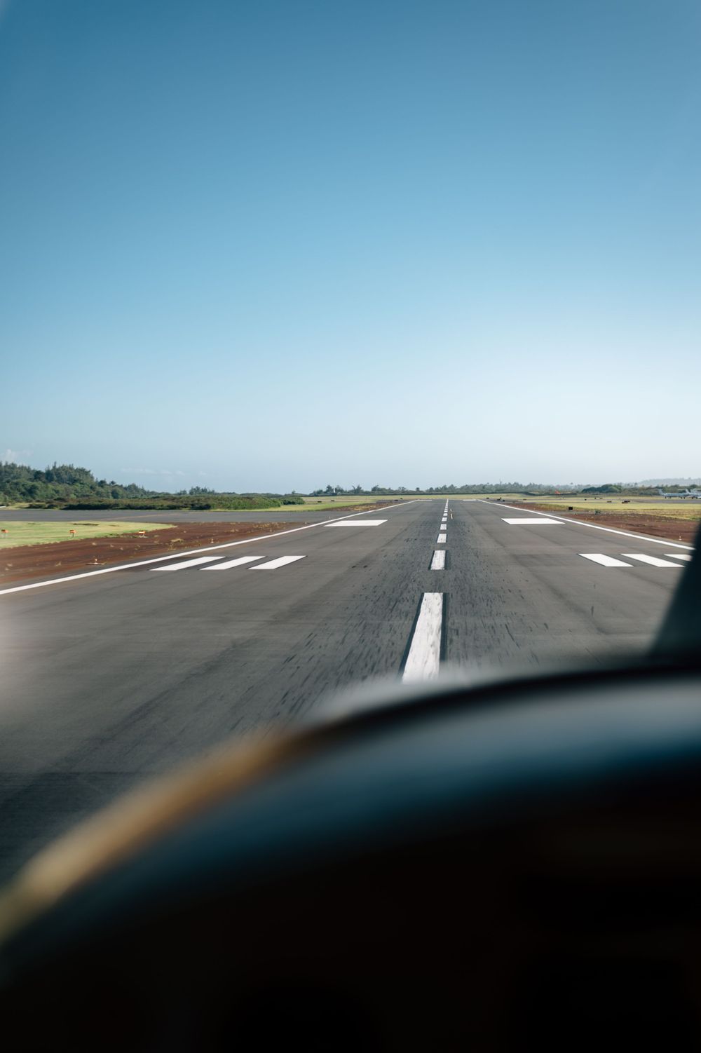 View of an airport runway from cockpit perspective on a clear day.