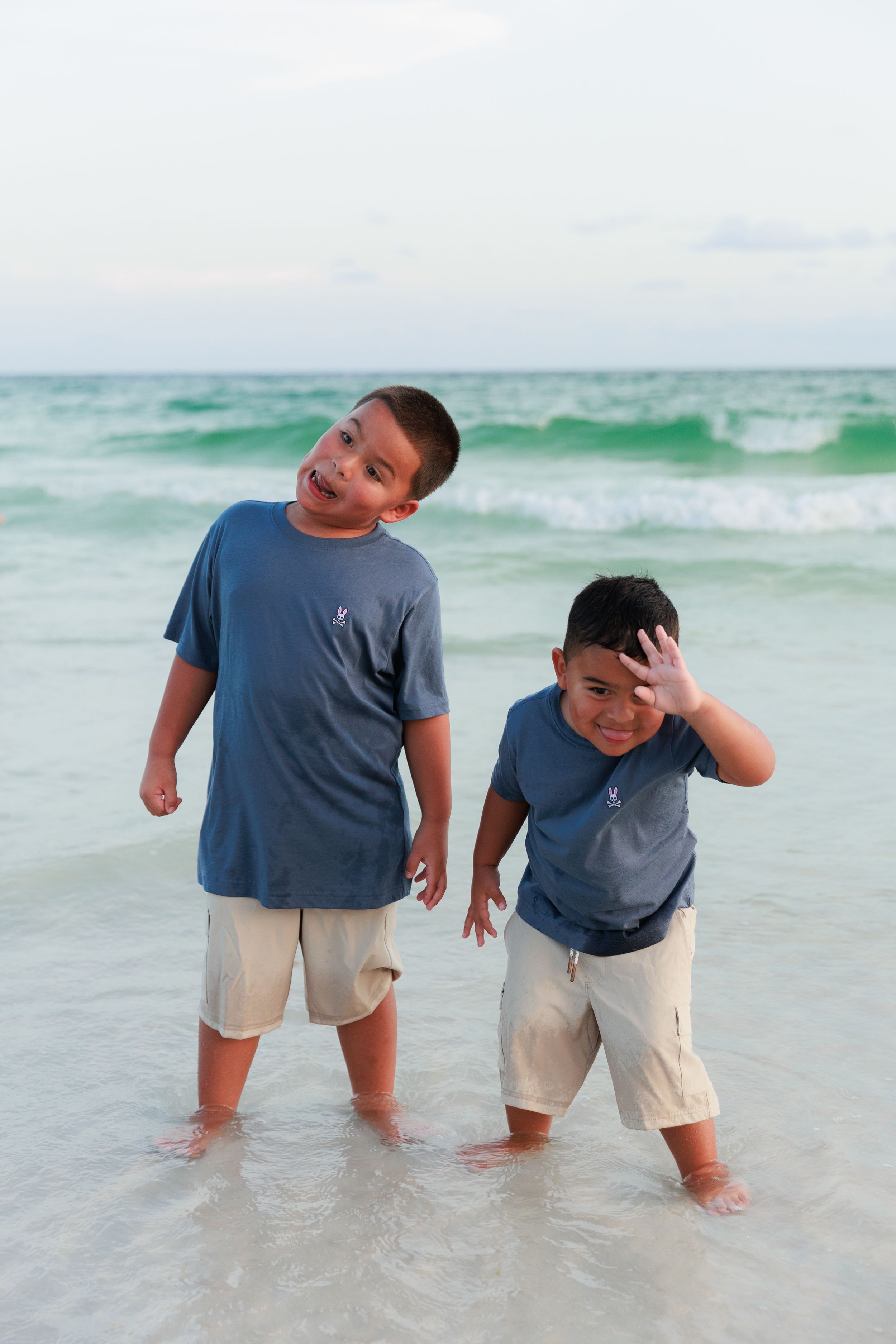 A sequence of playful moments at the beach shows someone splashing and enjoying the waves in a blue t-shirt and khaki shorts.