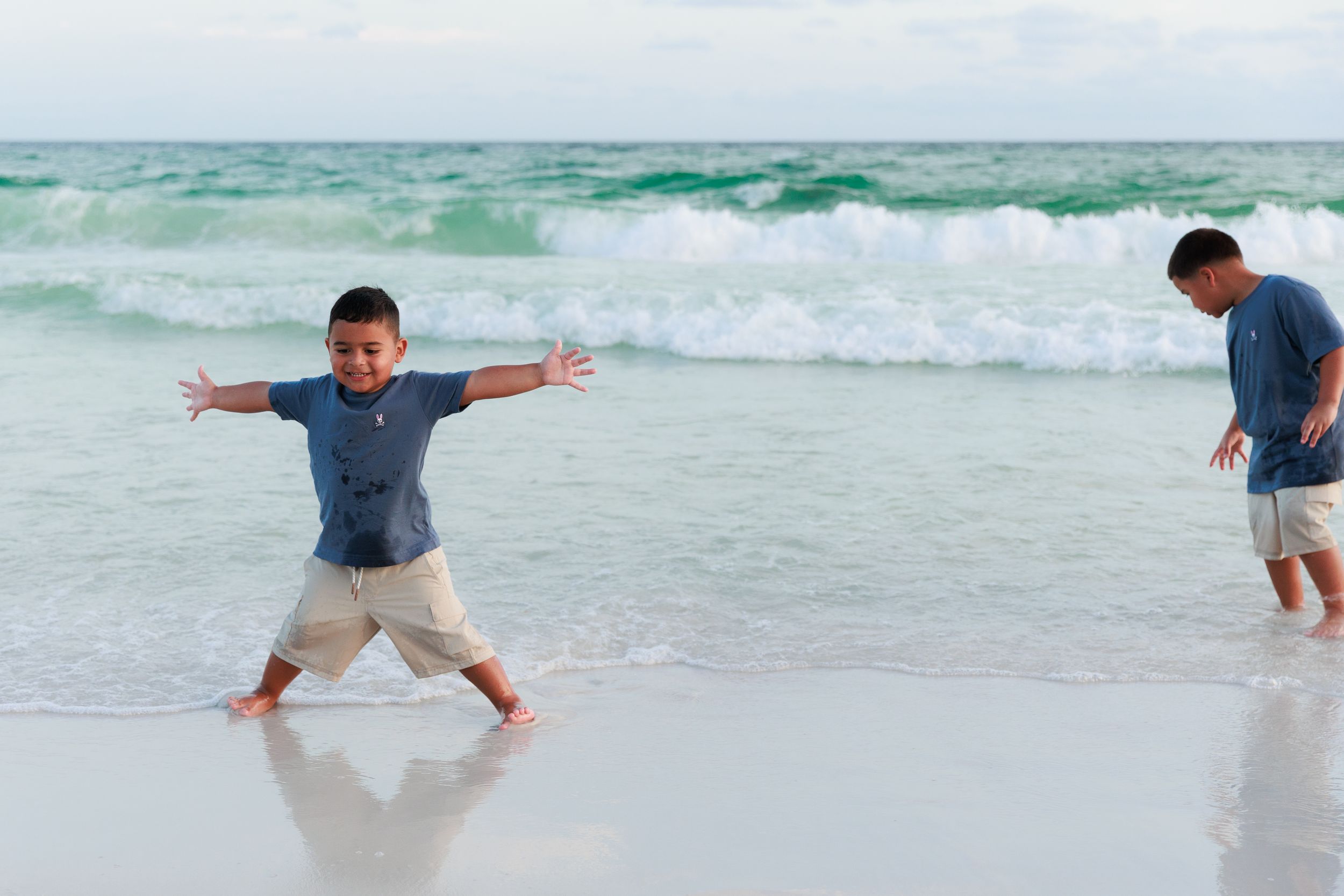 Four sequential photos show someone jumping and diving into ocean waves at the beach.