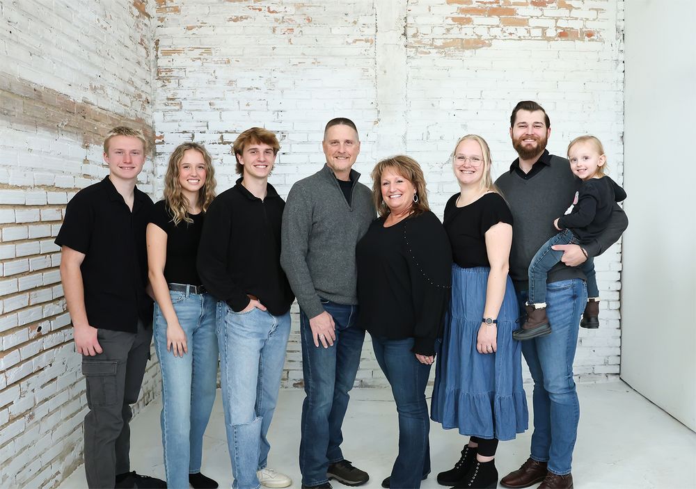 Family group photo series with multiple people wearing casual attire against a white brick wall.