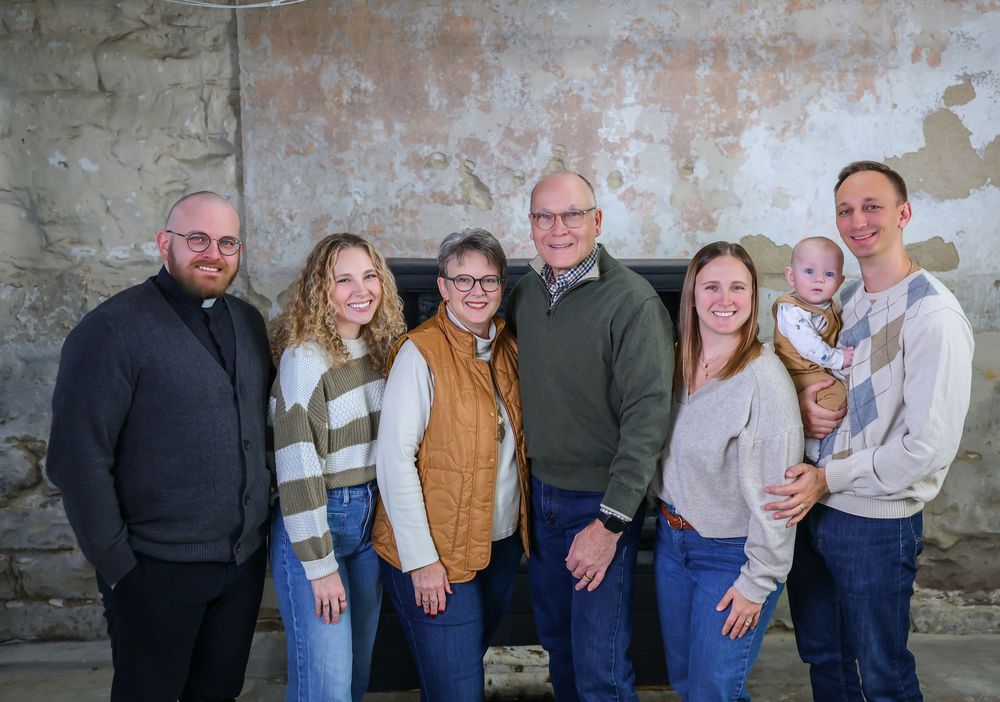 Extended family portrait session against weathered brick wall background.