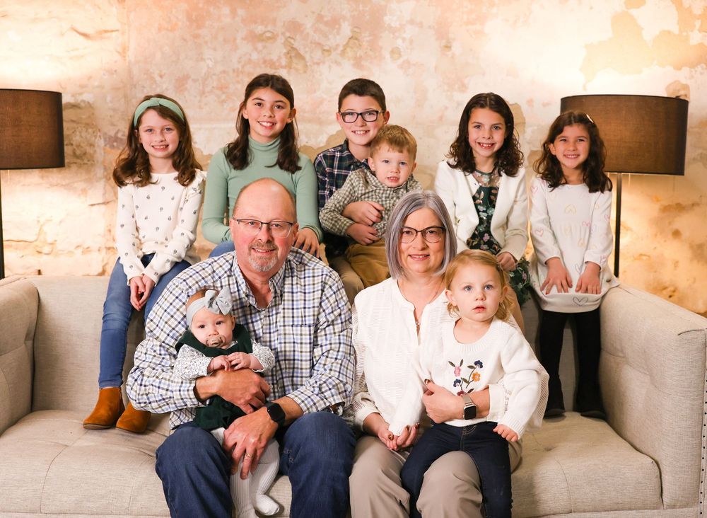 Family portrait session in a cozy indoor studio setting with neutral tones and warm lighting.