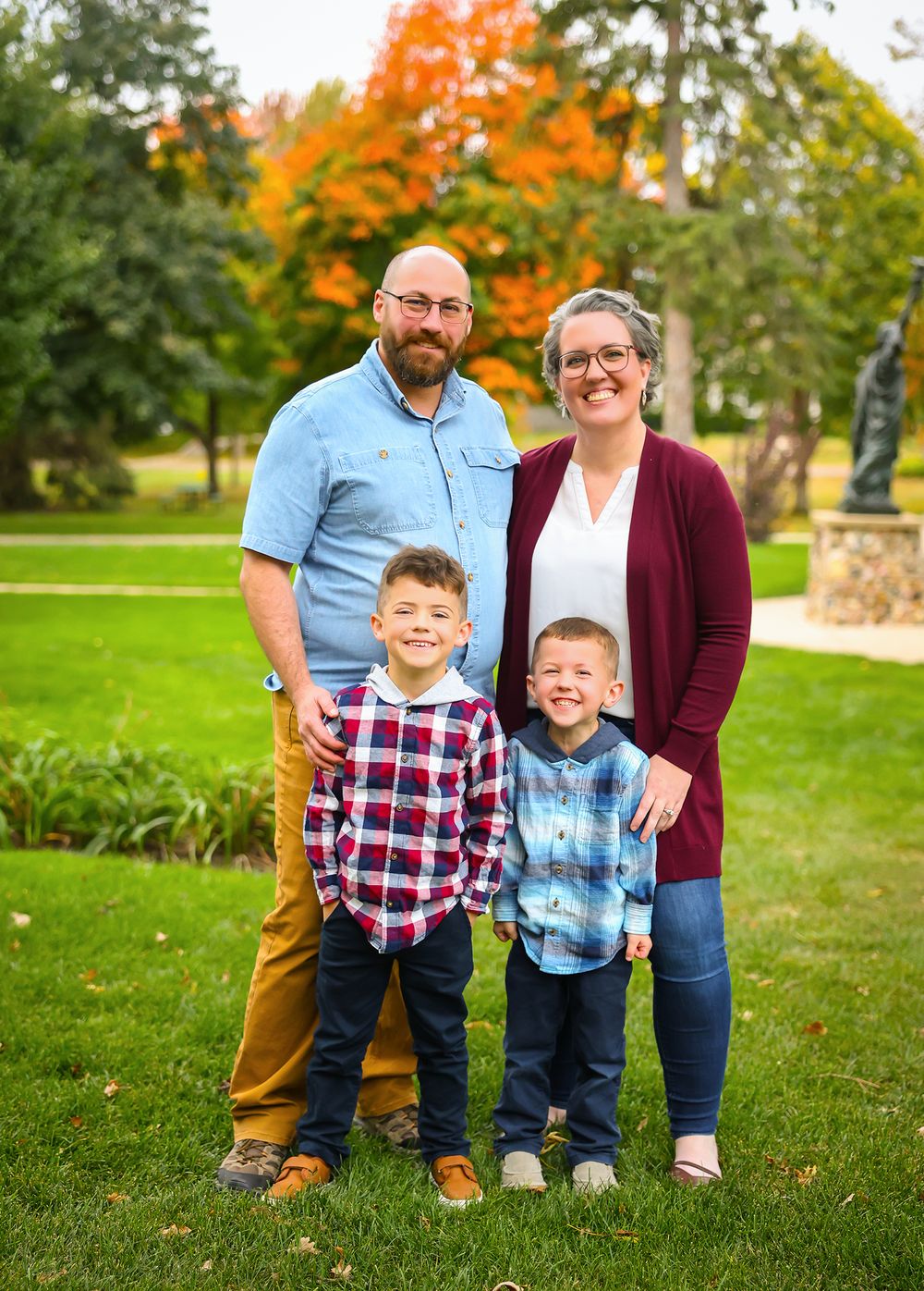 Family group photos on green grass with vibrant fall foliage in the background.