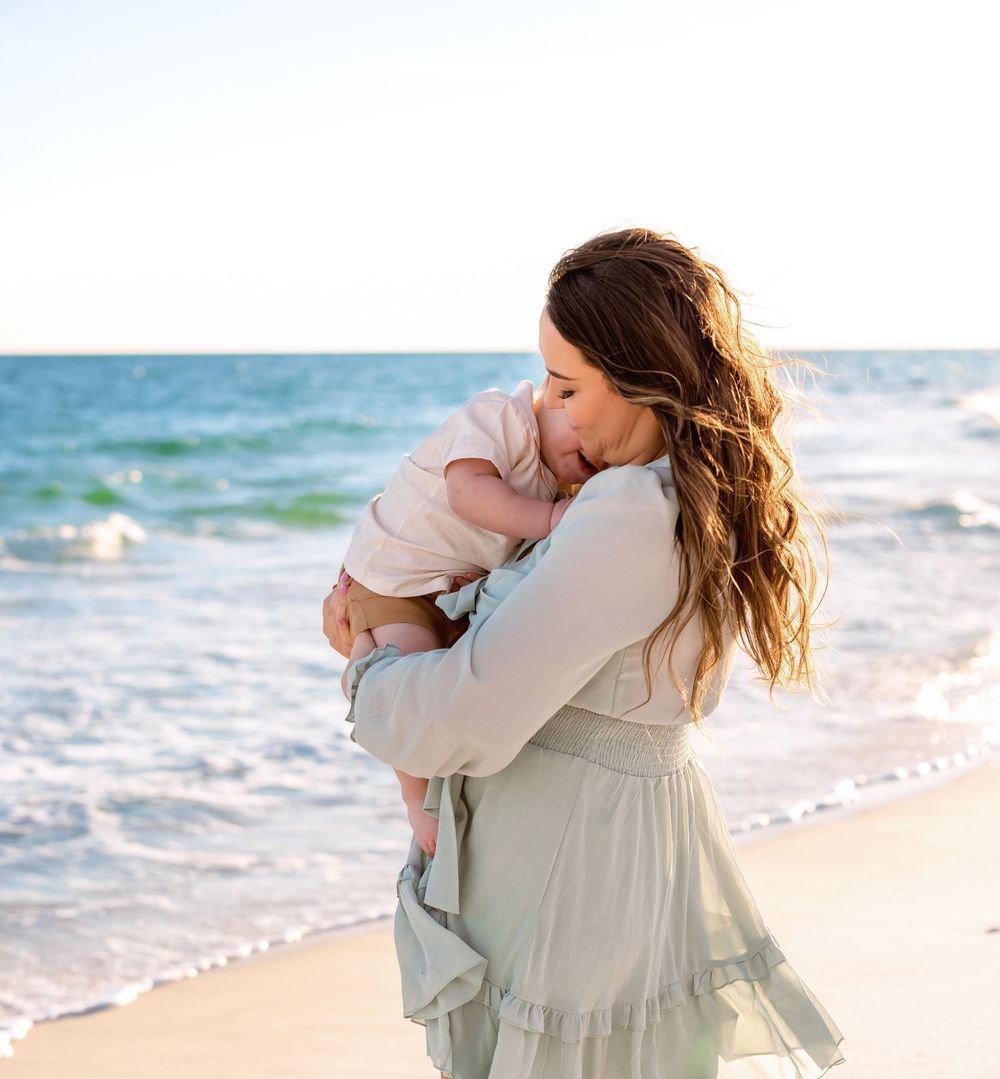 Couple embraces in romantic moment on sandy beach with ocean waves in background during golden hour.